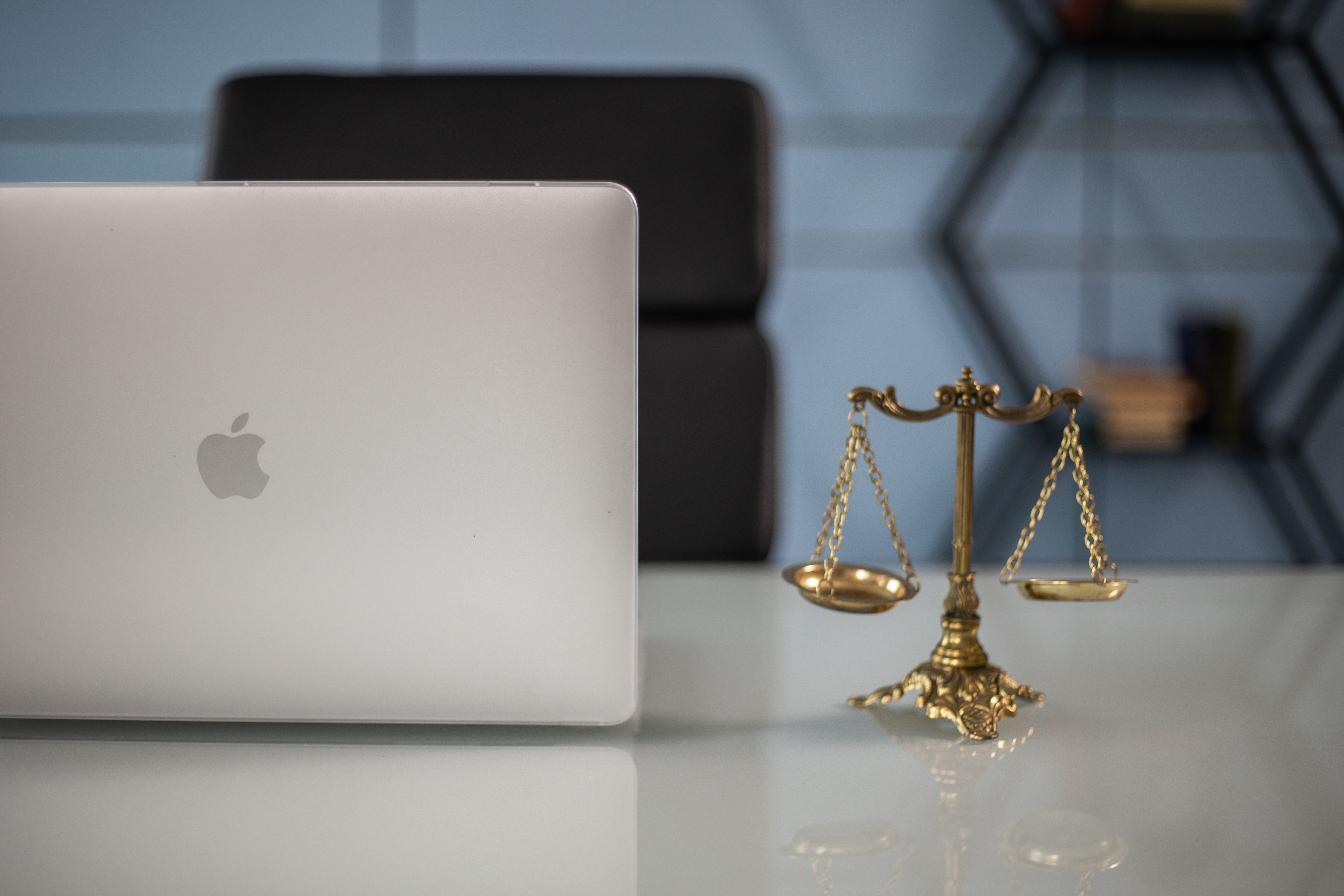 Gold justice scales beside a laptop symbolizing the balance of AI technology and the law