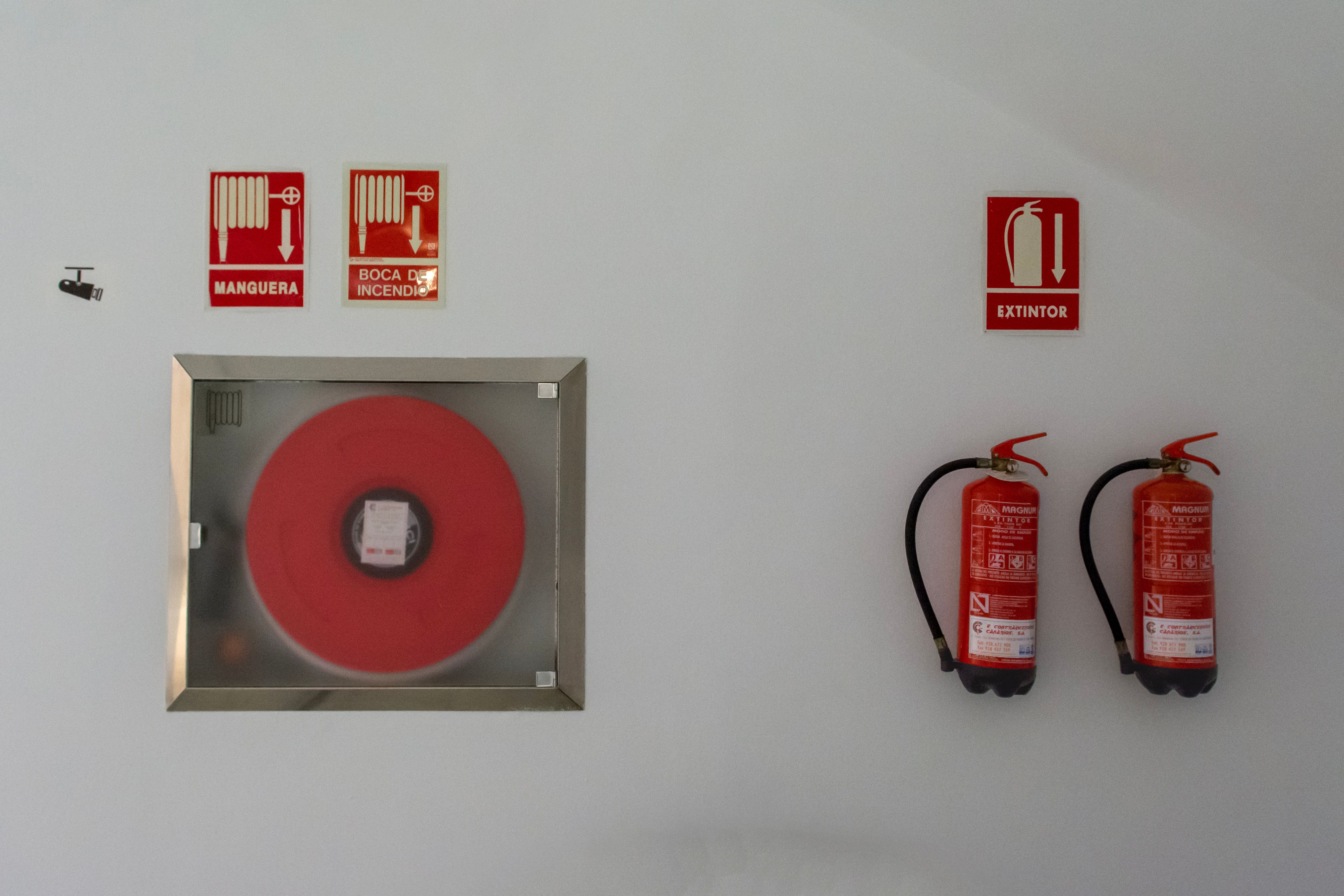 Fire safety equipment with extinguishers and hose reel mounted on a white wall